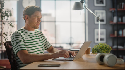 Aufkleber - Portrait of Handsome White Man Doing Remote Online Work on Laptop Computer while Sitting at his Desk. Freelancer Working From Home. Side View Shot