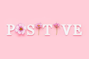 Wall Mural - Positive. Motivational quote from white letters and beauty natural flowers on pink background. Creative concept inspirational quote of the day