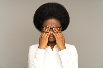 Sleepy young african business woman taking off glasses rubbing eyes feels tired after work on laptop isolated on gray background. Exhausted black girl feeling dry irritable eye strain. Fatigue concept