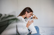 © Eva - happy caucasian woman at home cuddling on bed with cute jack russell dog. Pets, love and relax at home