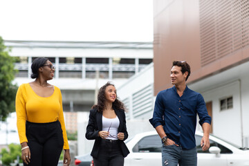 Three smiling businesspeople discussing about a meeting while walking in city.