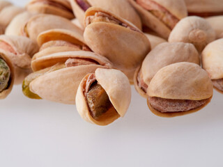 Pile of pistachios in the peel close-up on a white background. Isolated.