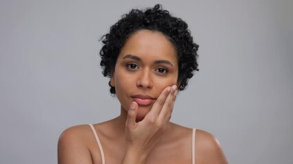 Wall Mural - beauty and people concept - portrait of happy smiling young african american woman with bare shoulders touching her face over grey background