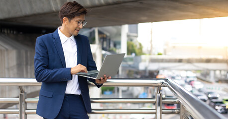 Wall Mural - Handsome asian businessman working outdoors with computer