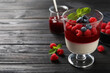 Delicious panna cotta with berries on black wooden table. Space for text