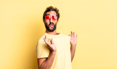 expressive crazy bearded man wearing sunglasses with a copy space against yellow wall