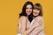 Two young smiling happy daughter mother together couple women wearing casual beige clothes looking camera hugging isolated on plain yellow color background studio portrait. Family lifestyle concept.