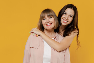 Wall Mural - Two young smiling happy satisfied daughter mother together couple women wearing casual beige clothes looking camera isolated on plain yellow color background studio portrait. Family lifestyle concept