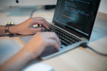 Close-up shot of man coding on laptop