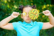 Girl In Blue Polo Shirt Holding Yellow And And Green Lollipops