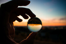 Person Holding Clear Glass Ball During Sunset