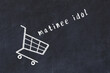 Chalk drawing of shopping cart and word matinee idol on black chalboard. Concept of globalization and mass consuming