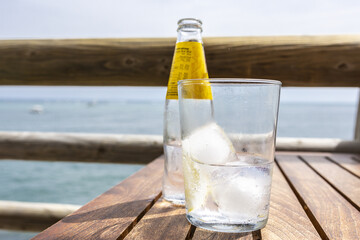 Poster - Bottle and glass of water with a slice of lemon and ice on a wooden table