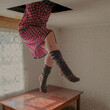 © Scopio - Woman's lower body in a red dress hanging from a ceiling above a wooden table