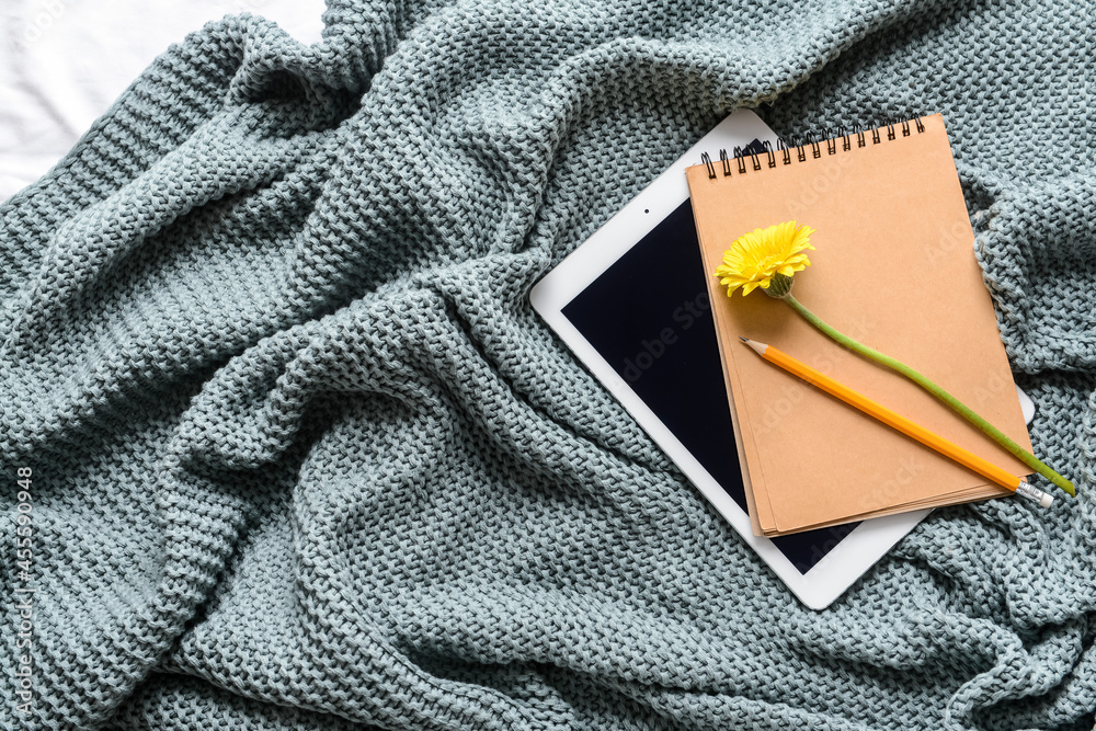 Stationery with flower and tablet computer on knitted plaid