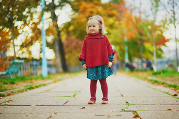 Wall Mural - Adorable toddler girl playing in autumn park in Paris, France