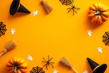 Happy Halloween Banner Design. Halloween Decorations, Pumpkins, Ghosts, Witches Hats, Brooms On Orange Background. Halloween Party Greeting Card Mockup With Copy Space. Flat Lay, Top View.