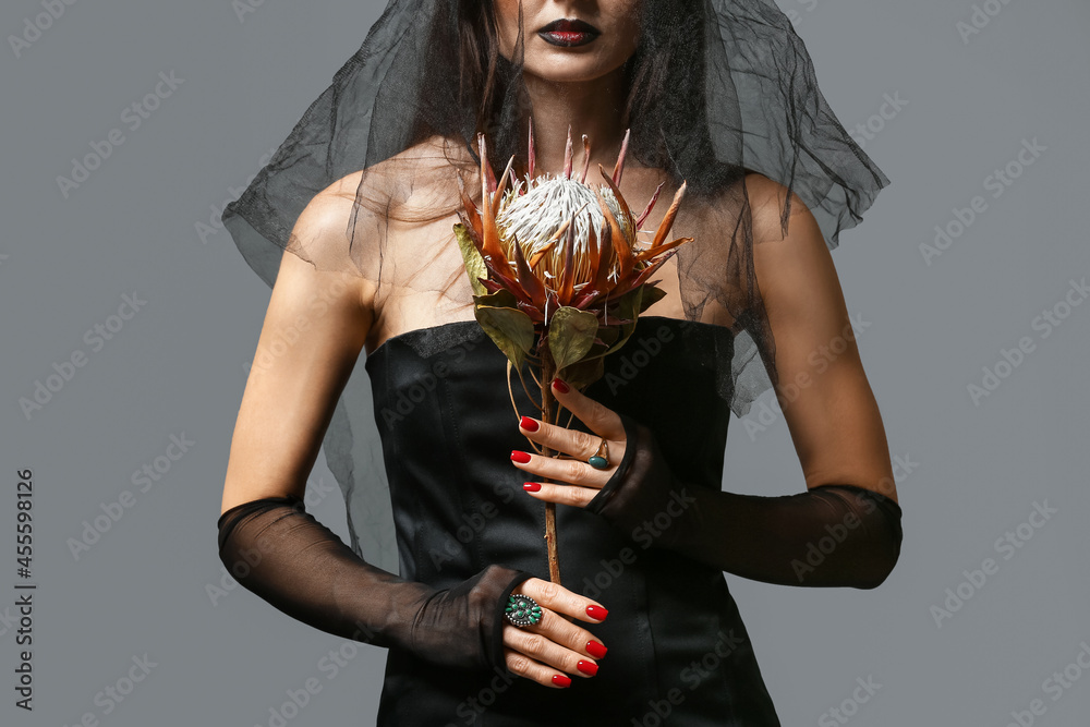 Beautiful woman dressed as witch for Halloween on grey background