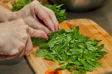 Sticker - Chef cuts basil according to the recipe for cooking on wooden board in the kitchen