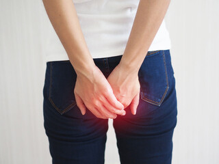 Young woman has anal cancer and touching her butt on white background. closeup photo, blurred.