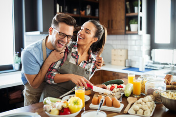 Wall Mural - Happy young couple have fun in modern kitchen while preparing fresh food