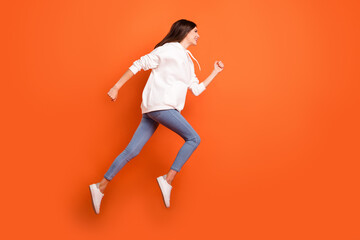 Wall Mural - Full length body size profile side view of pretty motivated cheerful girl jumping running isolated bright orange color background