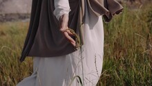 Jesus Is Walking On The Grass, Touching The Ears With His Hands. Close-up. There Are Traces Of A Crucifixion On The Hands. High Quality 4k Footage
