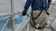 A worker attaches his full body harness to the scaffold, to work safely