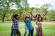 © amorn - Group of African American children playing and raising their hands in the park. Cheerful diverse black children dancing together outdoor