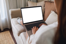 Mockup Image Of A Woman Working And Typing On Laptop Computer With Blank Screen On Sofa At Home