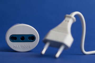 Wall Mural - Selective-focus shot of a plug adapter with a cable on a blue surface