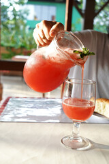 Canvas Print - Closeup shot of a hand pouring red cold lemonade