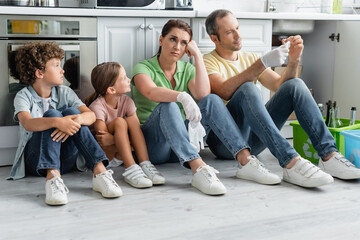 Wall Mural - Exhausted family with kids sitting near boxes with recycle sign in kitchen