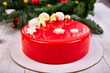 Mousse Christmas pastry cake dessert covered with red mirror glaze with new year decorations on garland lamps bokeh white background, Modern european cake Christmas theme. .