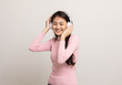 © Chanakon - Cheerful asian female teenager listen to the music with white headphone on isolated. Beautiful young woman in pink shirt hand touch a wireless headphone having fun with the music in  room.