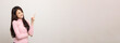 © Chanakon - Beautiful asian woman look into blank space. Smiling female wearing pink shirt on isolated white background. Attractive Teenager girl looking at empty space for text feeling excited and surprised.