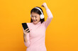 © Chanakon - Beautiful young asian women choose song and play music from smartphone connection with wireless headphone having fun. Teenage girl listen to the music enjoy relaxing on isolated yellow background.