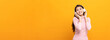 © Chanakon - Cheerful asian female teenager listen to the music with white headphone dancing on isolated yellow background. Beautiful young woman in hand touch a wireless headphone having fun with music.