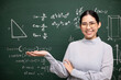 © Chanakon - Young asian teacher woman open hand palm up and video conference with student looking camera. Female teacher training the mathematics in classroom blackboard from online course.