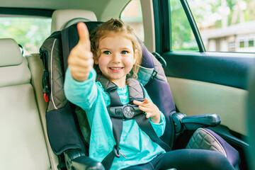 Small child sitting in a car doing thumb up