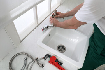 Canvas Print - Professional plumber fixing water tap in kitchen, above view