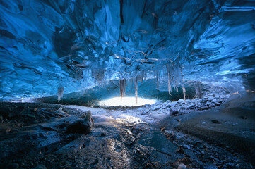 Photographer standing underground inside of a glacier, climate specific, vatnajokull National Park, amazing nature of Skaftafell, Entrance of an ice cave,Iceland