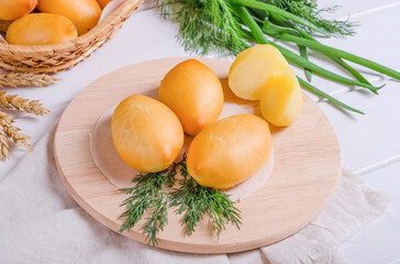 Fresh tasty patties with potato filling on a round wooden board on a wooden background