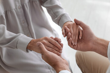 Religious people holding hands and praying together indoors, closeup