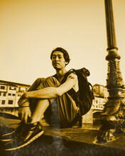 Smiling Man Sitting On Concrete Railing Beside Post In Florence