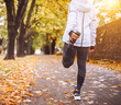 © Soloviova Liudmyla - Fit athletic woman doing stretching before jogging in the autumnal city park. Young fitness female runner stretching legs while warming up. Active running people concept image.