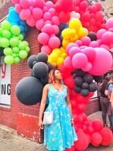 Woman In Floral Dress Standing Underneath Balloon Decoration Outdoors