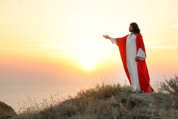 Poster - Jesus Christ raising hand on hills at sunset. Space for text