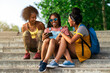 © Santi Nuñez/Stocksy - Three African teenage girls using a smartphones