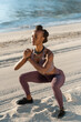 © Milles Studio/Stocksy - Black female athlete doing squats near sea